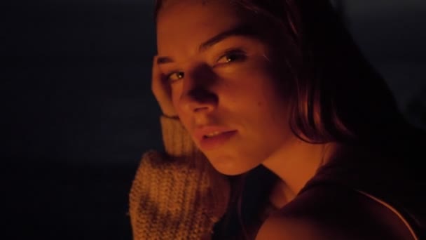 Unga kaukasiska ingefära tende tjej sitta vid elden i naturen och tittar på kameran, porträtt — Stockvideo