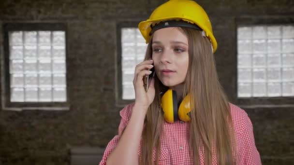 Νεαρό κορίτσι νευρικοί οικοδόμος μιλώντας στο τηλέφωνο, σύλληψη επικοινωνίας — Αρχείο Βίντεο