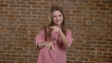 Genç güzel kız dans, gösterilen farklı duygular, canlı anlayışı, tuğla arka plan