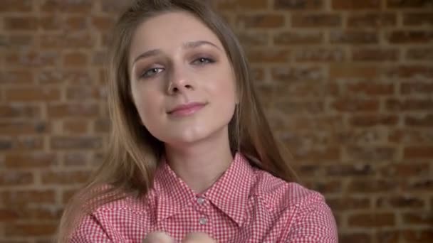 Mooi meisje toont hart zingen, kijken op camera, bakstenen bachground — Stockvideo
