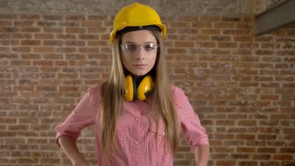 Jovem confiante menina construtor está cruzando braços, assistindo a câmera, fundo de tijolo — Vídeo de Stock