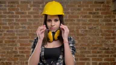 Doğruca kameraya bakarak ve koyarak gözlük, kadın builder, tuğla arka plan üzerinde kask içinde genç güzel çekici kadınlar