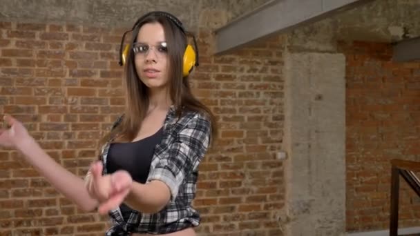 Nádherný atraktivní mladé ženy v brýle a sluchátka s jistotou při pohledu do kamery a křížení rukou, ženské tvůrce, cihlové pozadí — Stock video