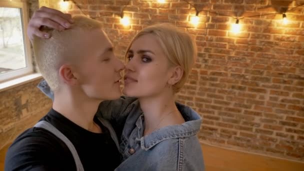 Jeune couple hipster amoureux fait de la vidéo, embrasser, concept de communication, concept d'amour, fond de brique — Video