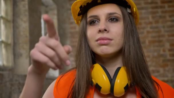 Jóvenes hermosas mujeres atractivas en casco y auriculares que cuentan algo, constructor femenino, ladrillo de fondo de la construcción — Vídeos de Stock