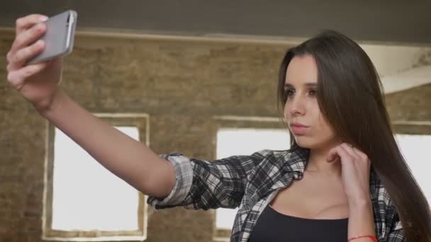 junge schöne attraktive Frauen in kariertem Hemd machen Selfie mit ihrem Handy, posieren für Foto, Backsteinbau Hintergrund