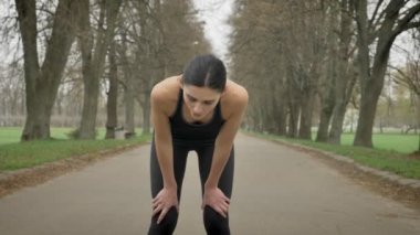 Genç spor kız yorgun bir dinlenme alır ve parkta çalıştırmaya yaz, sağlıklı yaşam, spor anlayışı devam edin