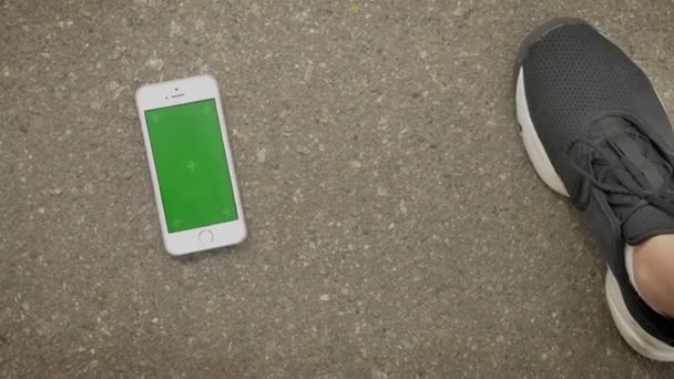 Sport girl picks up her smartphone from ground, chroma screen, communication concept — Stock Video