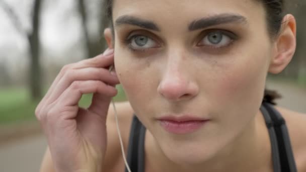 Молода мотивована дівчина носить навушники і бігає в парку влітку, здоровий спосіб життя, спортивна концепція — стокове відео