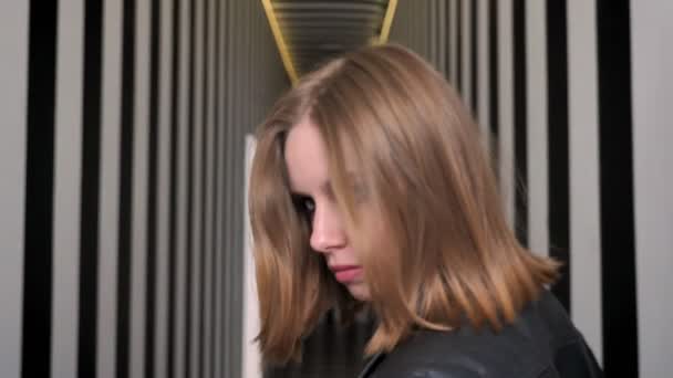 Молодые привлекательные женщины с тяжелым макияжем приглашая вас, уходя и поворачиваясь, уверенный, полосатый фон коридора — стоковое видео