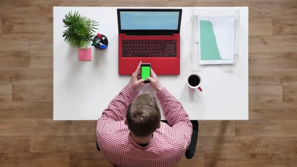 크로마 키, topshot, 커피와 노트북 책상 뒤에 앉아 전화에 입력 하는 젊은 남자 — 비디오