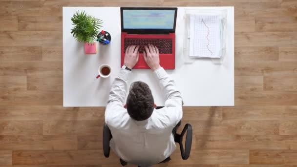 Jovem digitando no teclado, fechando laptop e se afastando, topshot, sentado atrás da mesa — Vídeo de Stock