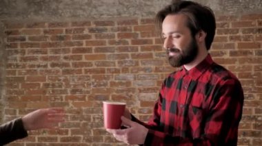 Sakallı genç çekici adam çay verir kız, iletişim kavramı, tuğla arka plan