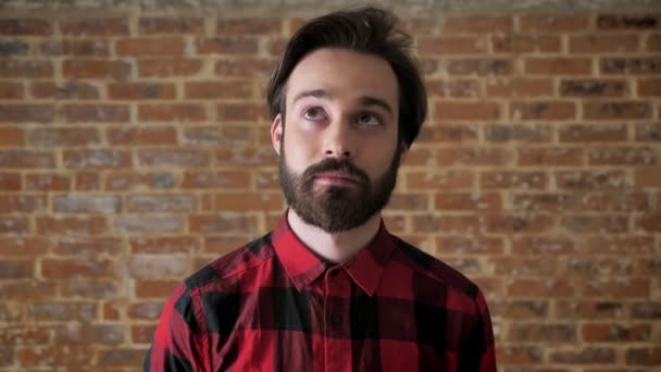 Молодой красивый парень с бородой создает идею, улыбаясь, думая процесс, кирпичный фон — стоковое видео