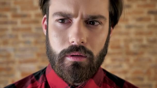 Joven hombre feliz guapo con barba está pensando, sonriendo, conciencia, fondo de ladrillo — Vídeos de Stock