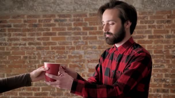 Ragazze mano dà a bell'uomo con la barba tazza di tè, concetto di comunicazione, sfondo di mattoni — Video Stock