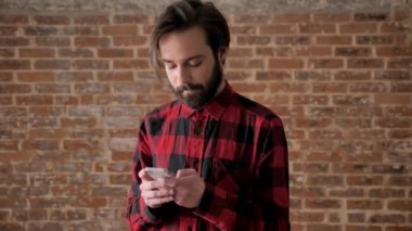 Sakallı yakışıklı delikanlı iletileri türleri onun smartphone, comunication kavramı, tuğla arka plan