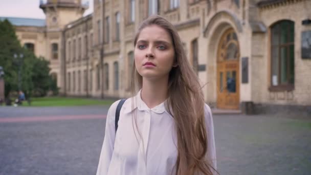 Όμορφη σοβαρή κοπέλα πηγαίνει από το Πανεπιστήμιο στη διάρκεια της ημέρας καλοκαίρι, σκέφτεται σύλληψη — Αρχείο Βίντεο