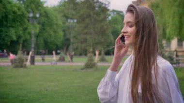 Genç güzel mutlu kız telefonda konuşurken ve parkta gündüz yaz, iletişim anlayışı içinde gidiş