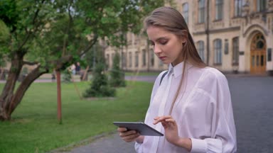 Genç güzel ciddi kız onun tablet üzerinde yaz, iletişim kavramı çalışır.