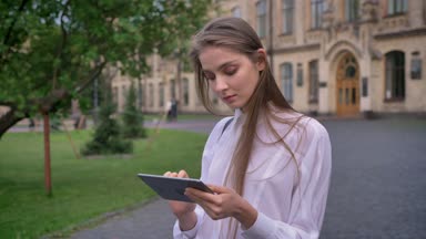 Genç çekici kız öğrenci onun tablet üzerinde yazında, kameraya, iletişim kavramı izlerken çalışır