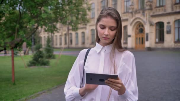 Mooie jonge meisje werken geconcentreerd op haar tablet in de zomer, communicatieconcept — Stockvideo