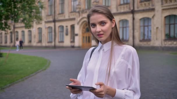 Joven estudiante hermosa chica trabaja en su tableta en verano, sonriendo, mirando a la cámara, concepto de comunicación — Vídeos de Stock