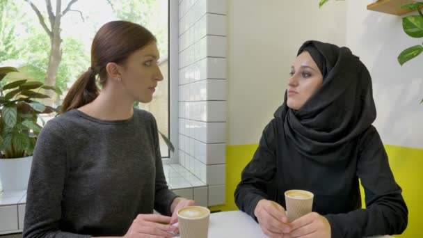 젊은 무슬림 여성 hijab 카페, 걱정 및 불안에 앉아 다른 여자에 게 뭔가 말하고에 꽤 — 비디오