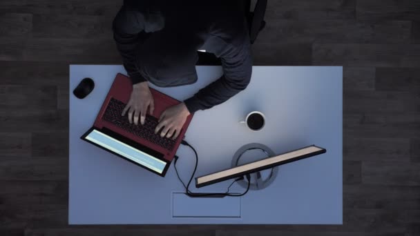Young man in black hoodie typing on laptop and then taking his flash drive and running away when lights turn on during night, top shot — Stock Video