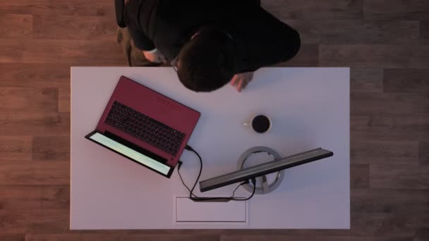 Directeur s'en va et quand les lumières éteignent jeune homme entrant et brancher sa clé USB et dactylographier sur ordinateur portable, plan du haut — Video