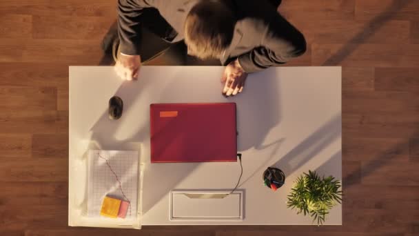 Mladý muž v brýlích a oblek v otevírání a psaní na notebooku, sedí za stolem, nejlepší záběr — Stock video