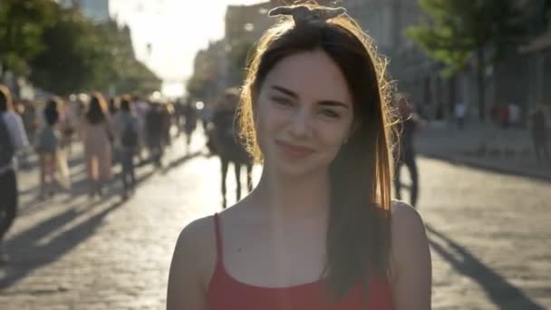 Portret van jonge mooie vrouw met gember haren permanent op straat, in de camera kijken en glimlachend, mensen rondlopen — Stockvideo