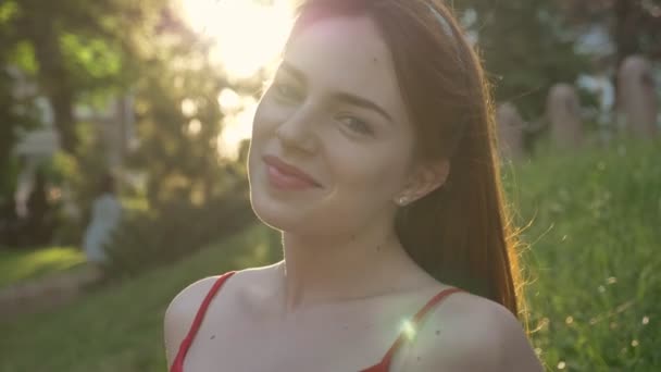 生姜の髪が公園に座ってカメラに探して 明るく輝く太陽と若い魅力的な女性のポートレート — ストック動画