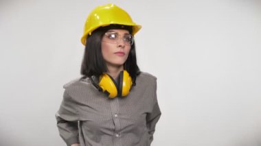 Genç Oluşturucusu kadının çapraz elinde kulaklık, gözlük ve kask, ciddi ifade, beyaz arka plan ile...