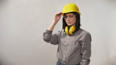 Kulaklık, gözlük ve kask dokunmadan kask, ciddi ifade, beyaz arka plan ayakta genç Oluşturucusu kadınlar