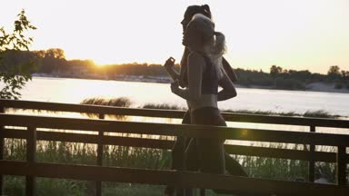 Nehir Parkı günbatımı, kilo kaybı sırasında çalışan iki genç güzel bayanlar fitness koşu, güzel görünüm modelleri