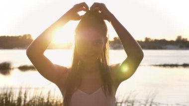 Kamera arayan kadın çekici genç portresi, onun at kuyruğu dokunmaktan ve gülümseyen, lens flare, nehir ve doğa arka plan