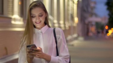 Genç çekici kız ileti onun Smartphone'da akşam yaz, gülüyor, iletişim kavramı yazmakta olduğunu.