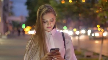 Genç çekici yer kız ileti onun Smartphone'da yaz aylarında akşam gülümseyen iletişim kavramı yazmakta olduğunu