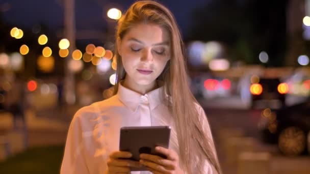 Young beautiful girl is typing message on her tablet in evening in summer, thinking concept, communication concept — Stock Video
