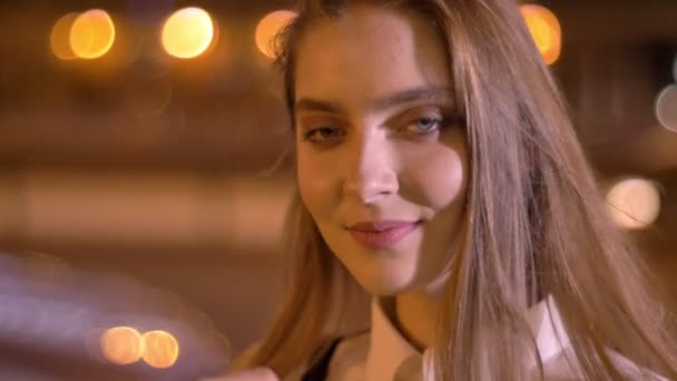 Junges süßes Mädchen schaut abends im Sommer vor die Kamera, berührt ihre Haare, flirtet mit ihr — Stockvideo