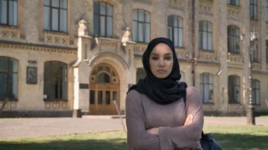 Kendine güvenen genç Müslüman kız kameraya, arka planda, dini kavramı bina izlerken kollu yaz aylarında gündüz geçti duruyor