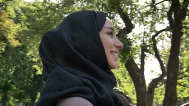 Junges fröhliches muslimisches Mädchen im Hijab lächelt und schaut im Sommer tagsüber an der Universität zu, religiöses Konzept, Konzeptstudium — Stockvideo