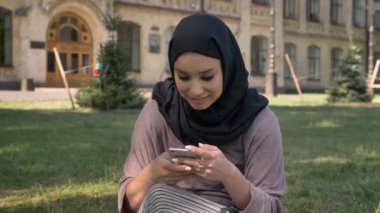 Hijab Müslüman kız Genç güzel smartphone vasıl gündüz yaz, kameraya, gülümseyen, Bina arka plan, religiuos kavramı, iletişim kavramı üzerinde izlerken izliyor
