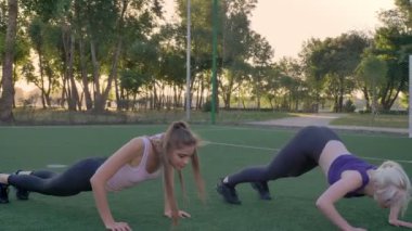 İki genç kadının üzerinde futbol sahası Park, kilo kaybı, egzersiz fitness modelleri germe