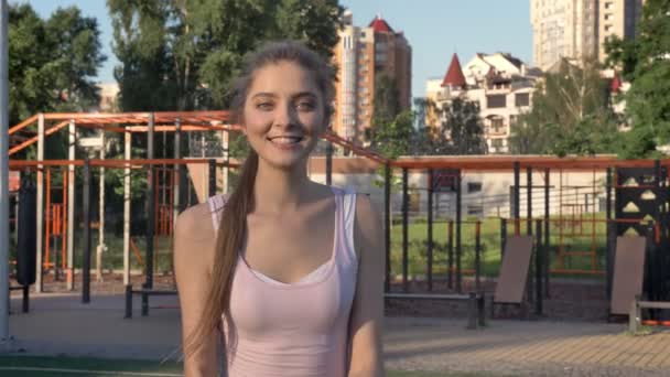 Молодая красивая женщина приглашает вас на открытый тренажерный зал и бежит к нему, улыбаясь, счастлив — стоковое видео