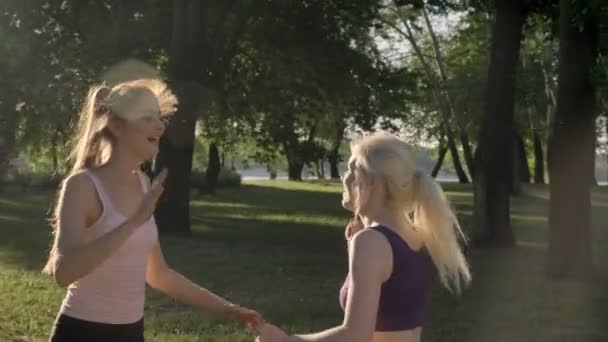 两个年轻漂亮的女人 enjoing 他们早上的工作在公园和给高五, 微笑和快乐, 健康的生活方式 — 图库视频影像