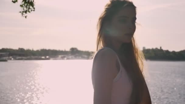 Young charming woman waving, touching her long hair and turning away, river background — Stock Video