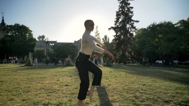 Jovem extraordinária menina ousada está dançando na grama no parque à luz do dia no verão, assistindo a câmera, conceito de movimento, vista inferior — Vídeo de Stock