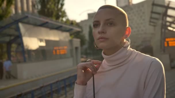 Young extraordinary bold girl dreamer is waiting for train on railway station in daytime in summer, urban concept — Stock Video